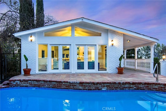 back house at dusk featuring a patio