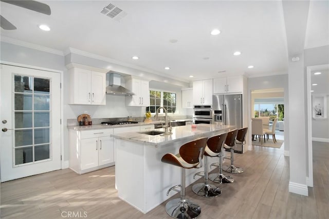 kitchen with white cabinetry, wall chimney range hood, sink, and appliances with stainless steel finishes