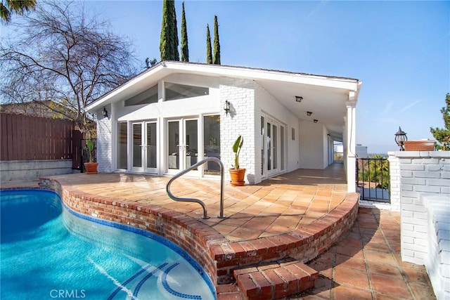 rear view of property featuring a patio, french doors, and a fenced in pool