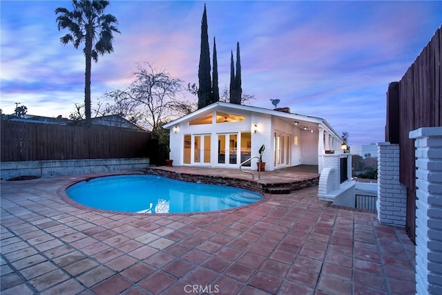 pool at dusk with a patio area