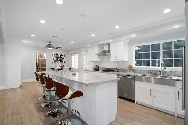 kitchen featuring a kitchen island, appliances with stainless steel finishes, white cabinets, and wall chimney exhaust hood