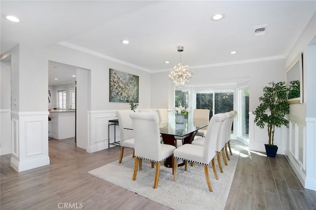 dining room featuring crown molding, light hardwood / wood-style flooring, and a chandelier