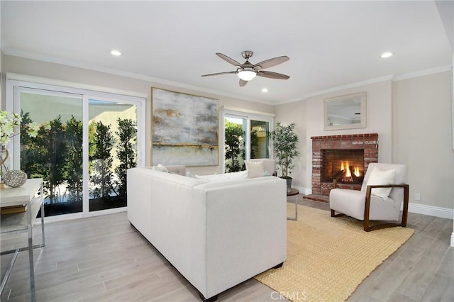 living room featuring crown molding, ceiling fan, a fireplace, and light hardwood / wood-style floors