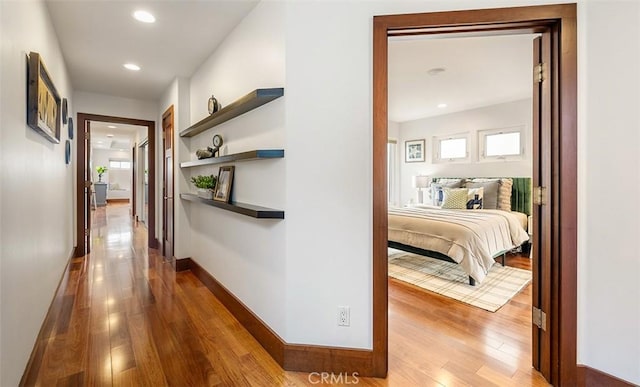 corridor with light wood-style flooring, baseboards, and recessed lighting