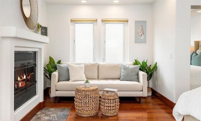 living room featuring dark wood-type flooring, recessed lighting, a glass covered fireplace, and baseboards