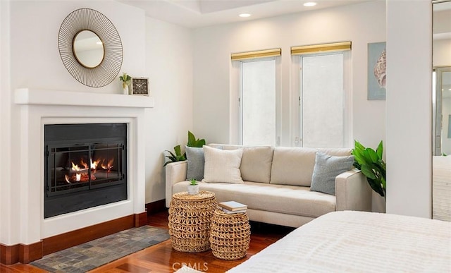 interior space with recessed lighting, wood finished floors, and a glass covered fireplace