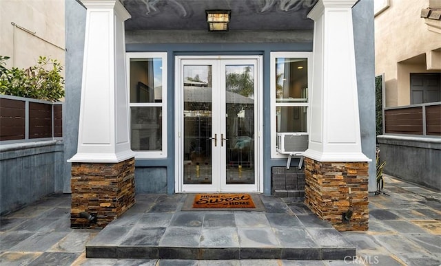 view of exterior entry featuring stone siding, stucco siding, and french doors