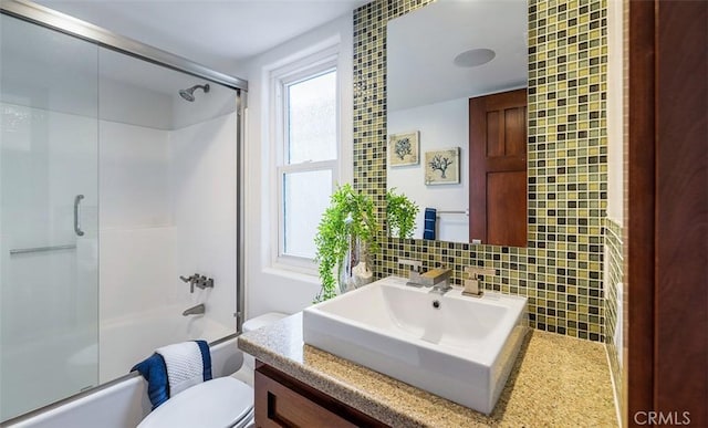 bathroom with toilet, enclosed tub / shower combo, backsplash, and vanity