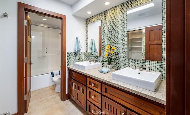 full bath featuring toilet, tasteful backsplash, enclosed tub / shower combo, and a sink