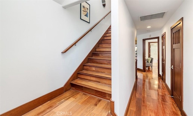 stairway with baseboards, visible vents, wood finished floors, and recessed lighting