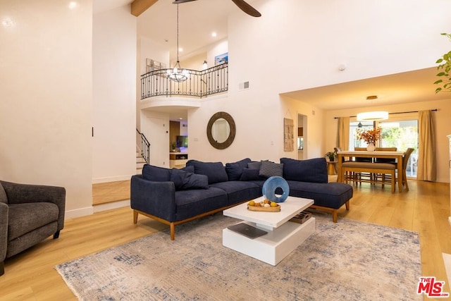 living room featuring a high ceiling, hardwood / wood-style floors, ceiling fan, and beamed ceiling