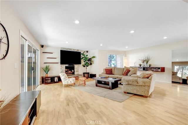 living area featuring a fireplace, light wood-style flooring, and recessed lighting