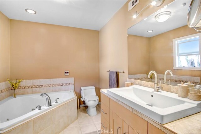 bathroom with a relaxing tiled tub, vanity, tile patterned flooring, and toilet