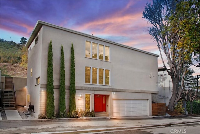 view of front of property with stairs, a garage, and stucco siding