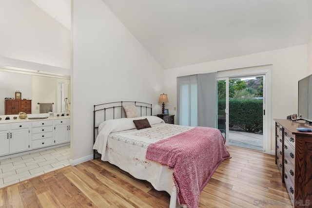 bedroom featuring access to exterior, light hardwood / wood-style flooring, high vaulted ceiling, and ensuite bathroom