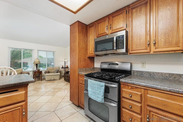 kitchen featuring stainless steel appliances, vaulted ceiling, and light tile patterned floors