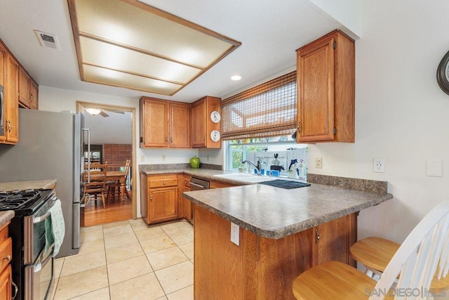 kitchen with light tile patterned flooring, sink, a kitchen breakfast bar, range with two ovens, and kitchen peninsula