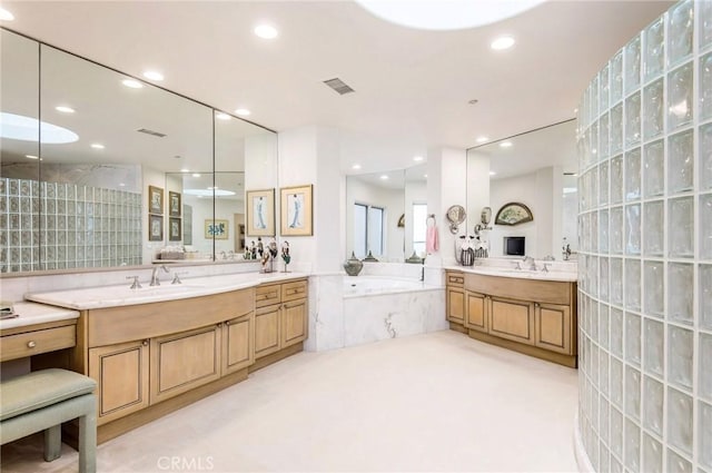 bathroom with vanity and tiled tub