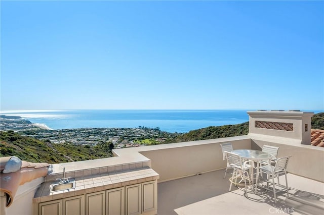 balcony with a patio area, an outdoor kitchen, and a water view