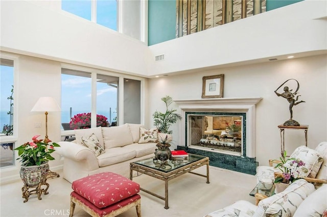 living room featuring a premium fireplace and a towering ceiling