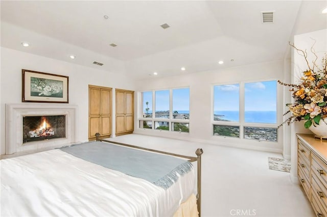 bedroom featuring a high end fireplace and a raised ceiling