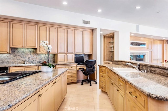 kitchen featuring light stone counters, built in desk, sink, and light tile patterned floors