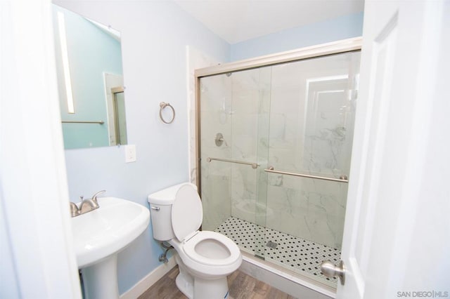 bathroom with toilet, wood-type flooring, sink, and a shower with shower door