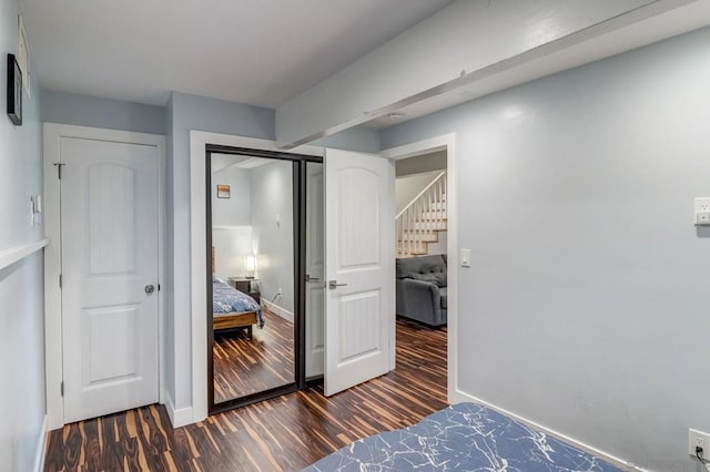 bedroom with dark wood-type flooring and a closet