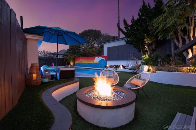 patio terrace at dusk with a fire pit and a lawn