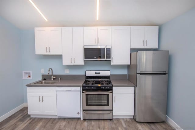 kitchen with hardwood / wood-style flooring, stainless steel appliances, sink, and white cabinets