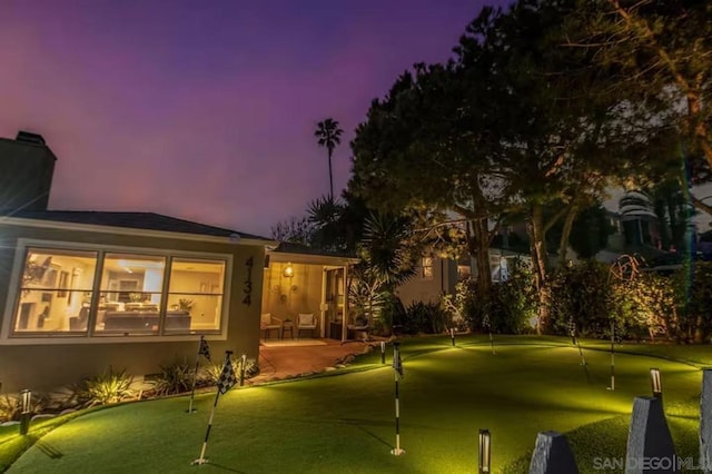 back house at dusk with a patio area