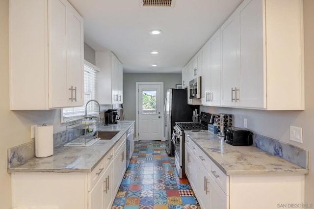 kitchen featuring light stone countertops, appliances with stainless steel finishes, sink, and white cabinets