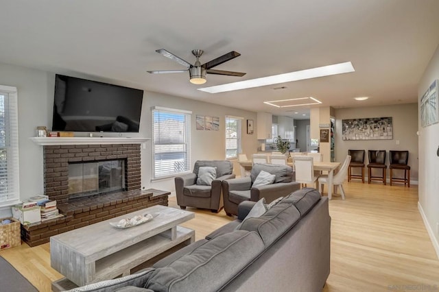 living room featuring light hardwood / wood-style flooring, a fireplace, and ceiling fan