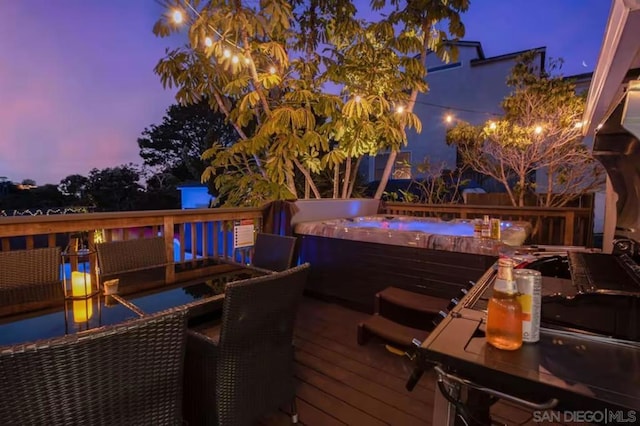 deck at dusk featuring a hot tub