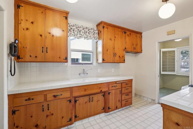 kitchen featuring tile counters, decorative light fixtures, sink, and backsplash