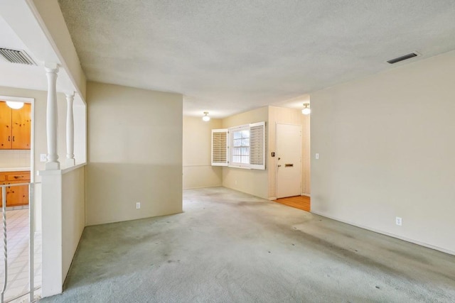 carpeted spare room with decorative columns