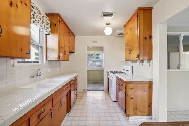 kitchen with tasteful backsplash, a healthy amount of sunlight, sink, and gas range gas stove