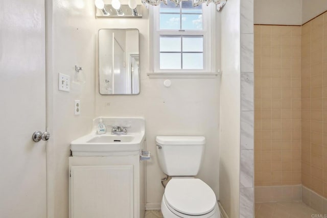 bathroom with vanity, tiled shower, and toilet