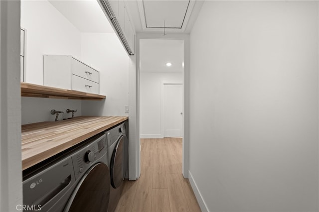 clothes washing area with washer and clothes dryer and light wood-type flooring