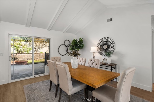 dining area with hardwood / wood-style flooring and vaulted ceiling with beams