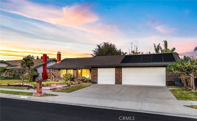 ranch-style home with a garage and solar panels