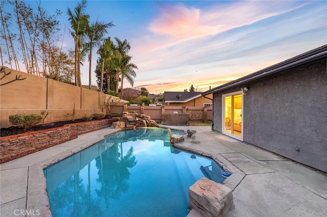 pool at dusk with a patio area