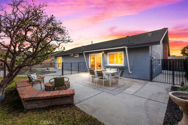 back house at dusk with a patio area