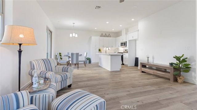 living room with sink, a chandelier, and light hardwood / wood-style flooring