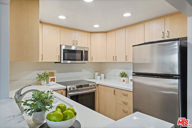 kitchen with light brown cabinetry, stainless steel appliances, and kitchen peninsula