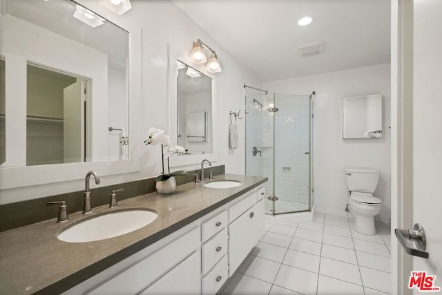 bathroom with vanity, toilet, a shower with shower door, and tile patterned flooring