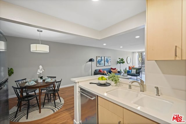 kitchen featuring sink, dishwasher, hanging light fixtures, light brown cabinets, and light wood-type flooring