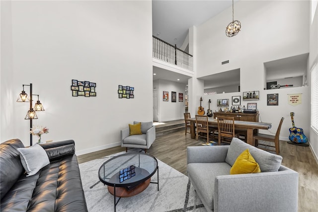 living room with a towering ceiling, hardwood / wood-style floors, and a notable chandelier