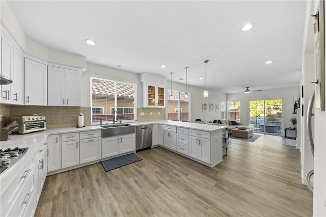 kitchen with white cabinetry, sink, hanging light fixtures, and kitchen peninsula