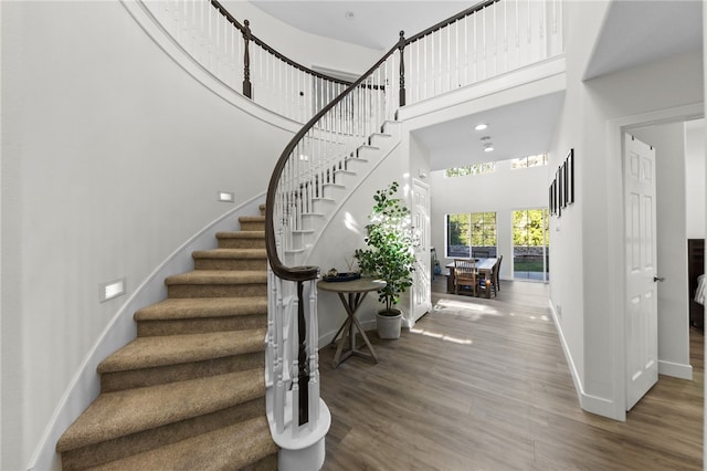 stairs with a high ceiling and hardwood / wood-style flooring